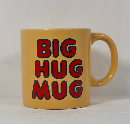 Yellow mug with red and black text 'BIG HUG MUG' on a white background