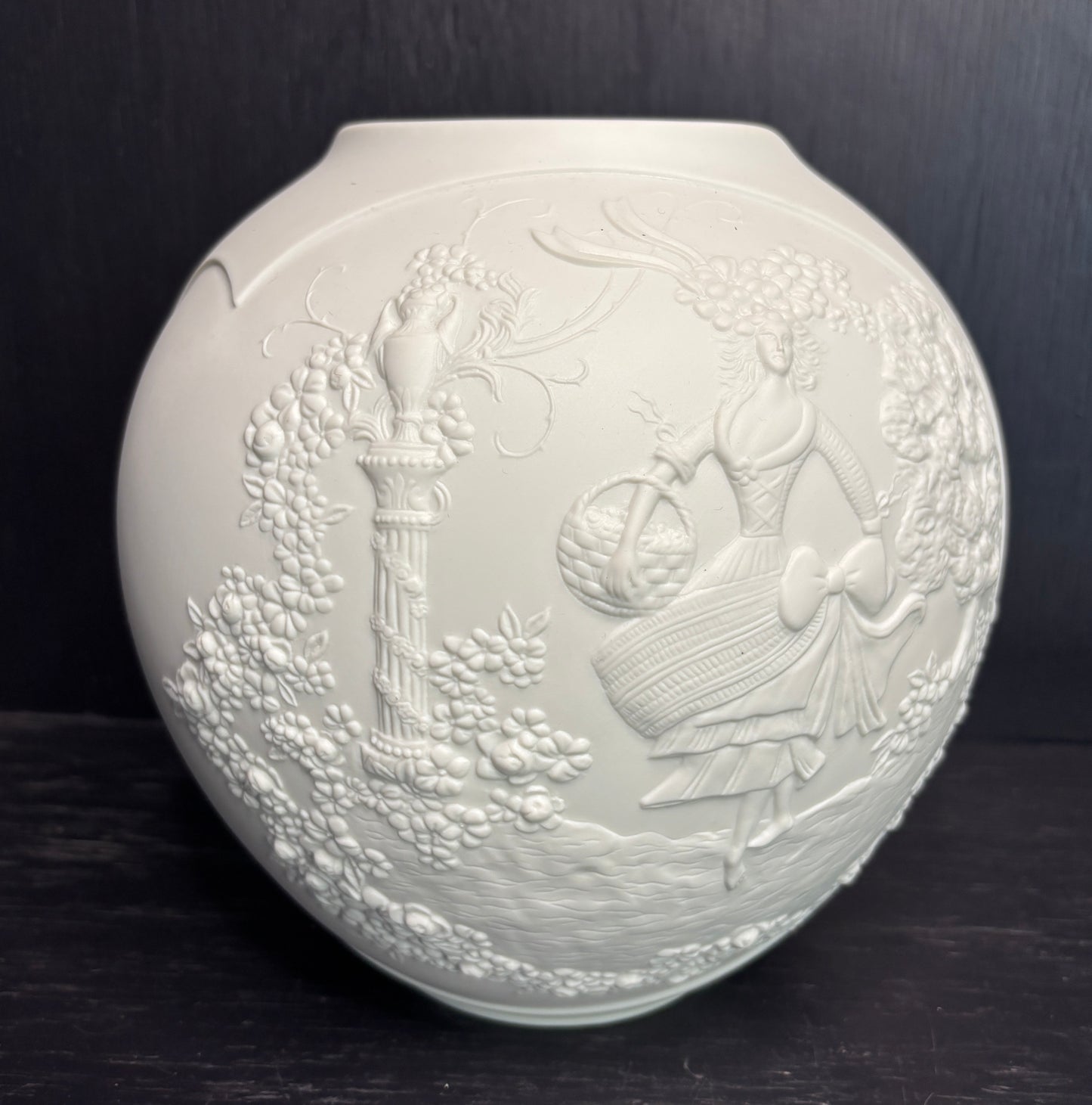 Decorative white vase with embossed design on a dark background