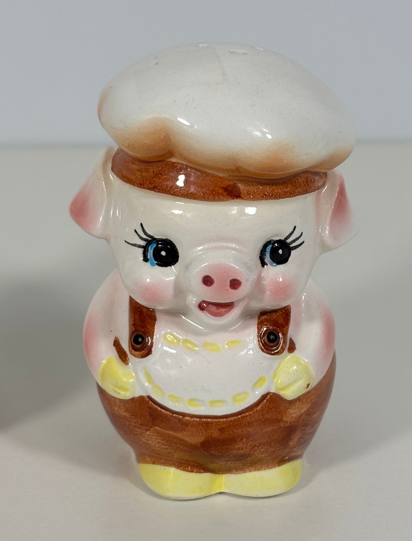 Ceramic piggy salt shaker with a chef's hat and apron on a white background