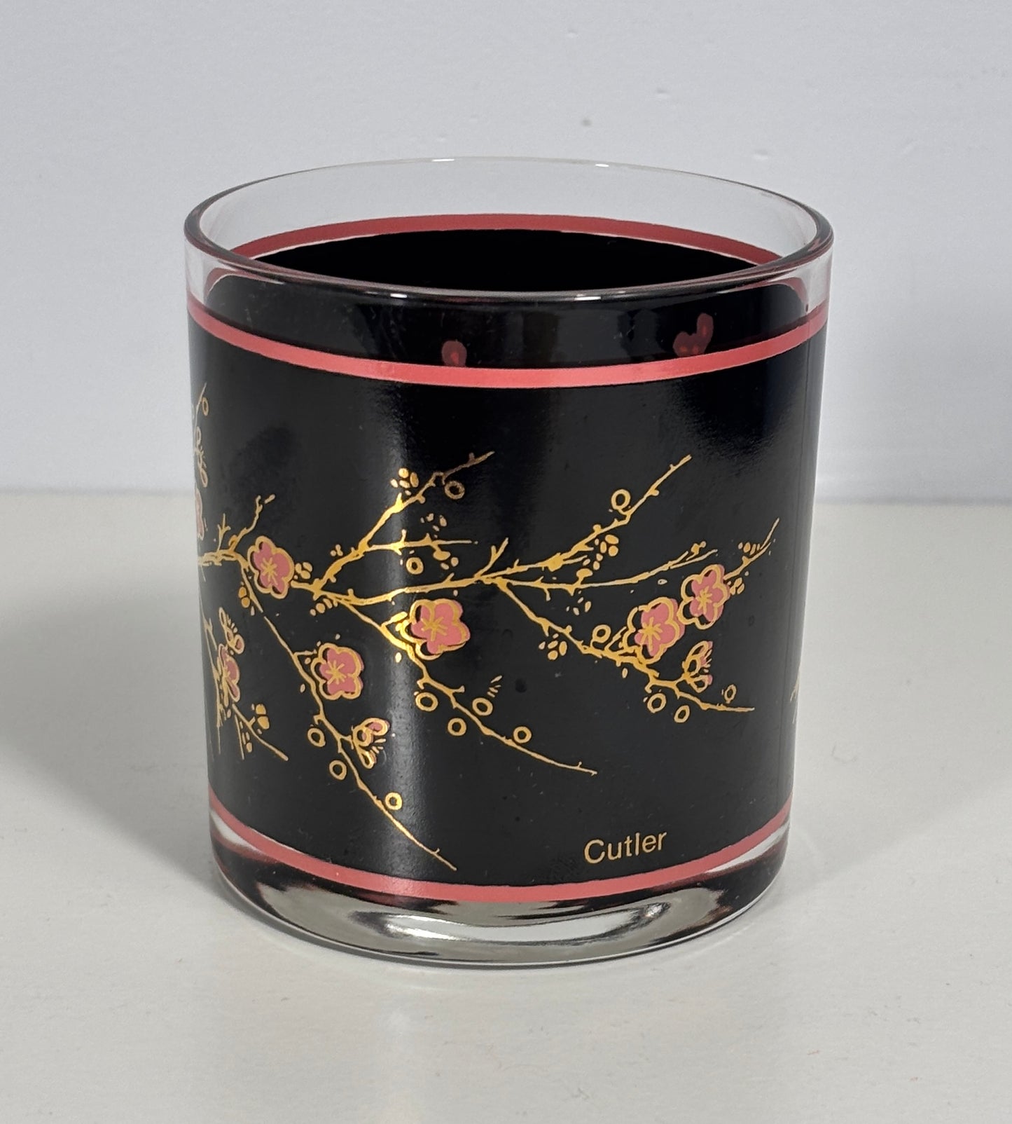 Glass tumbler with black interior, floral design, and 'Cutler' branding on a white background