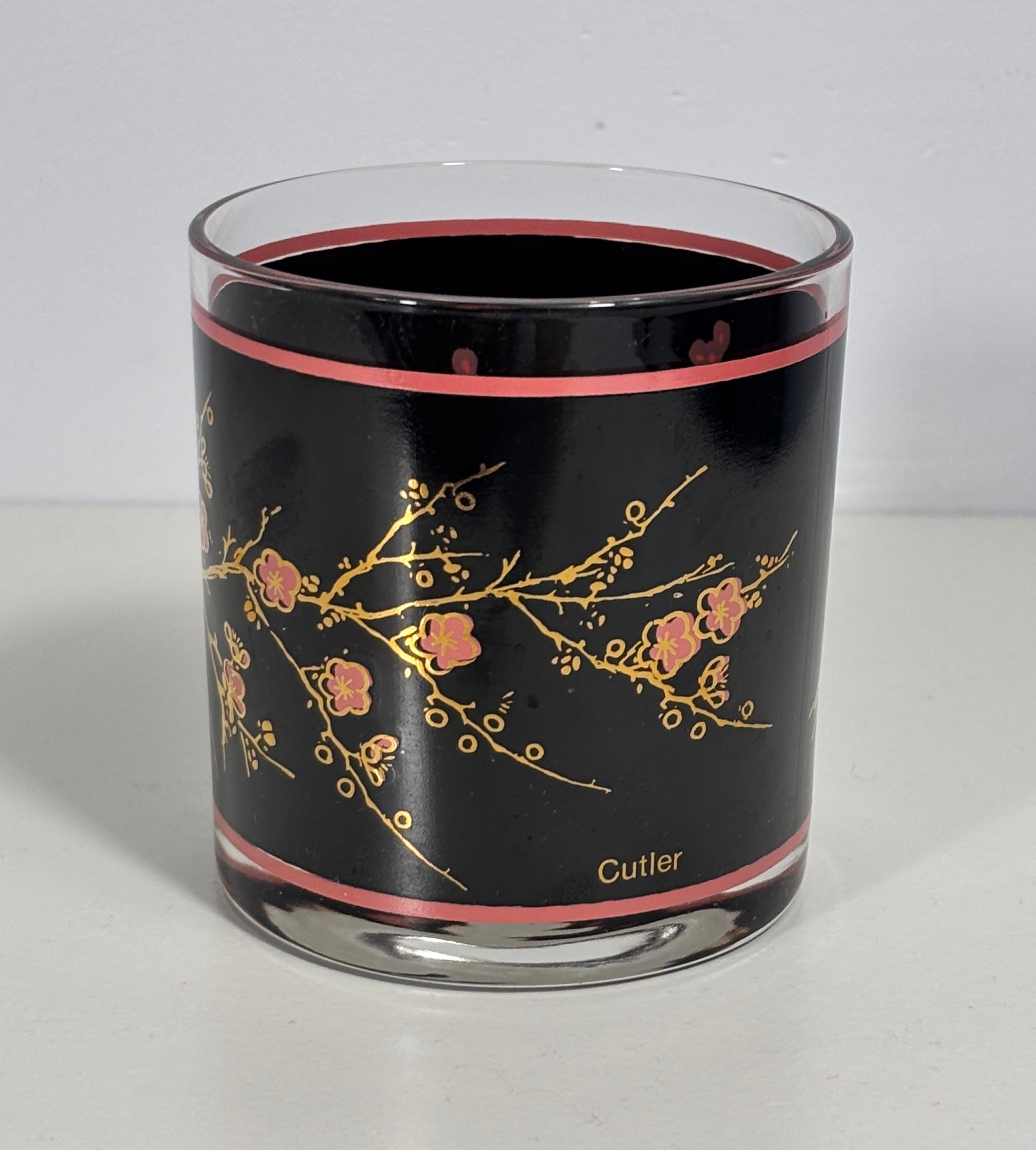 Glass tumbler with black interior, floral design, and 'Cutler' branding on a white background