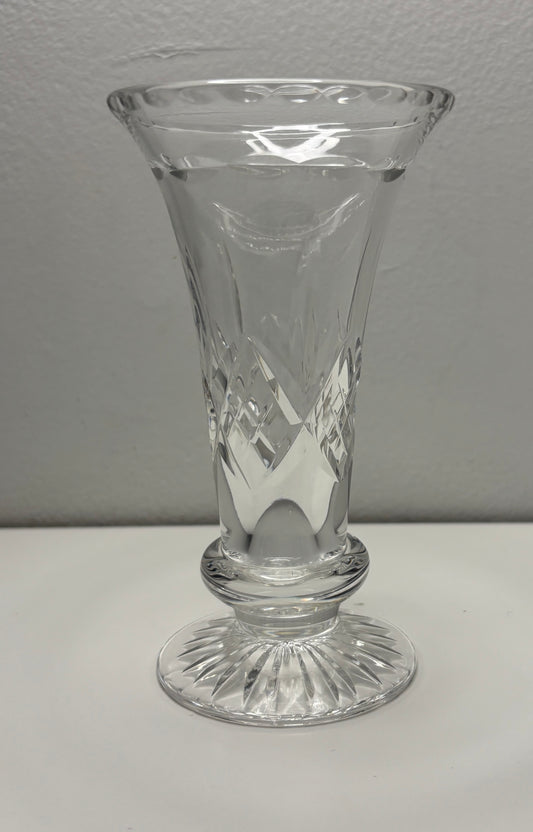 Clear glass vase with etched design on a white surface and gray background