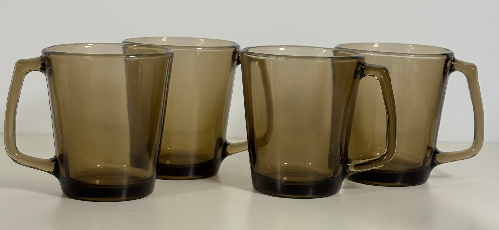 Four brown glass mugs with handles on a white background
