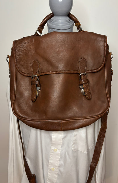 Brown leather satchel on a mannequin against a plain background