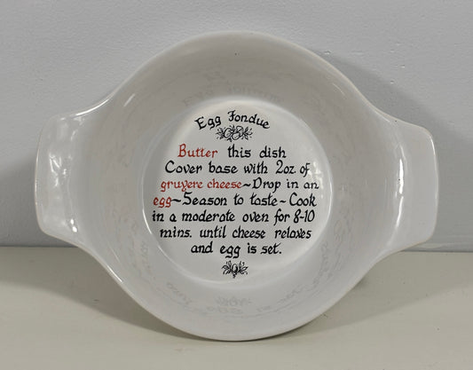 A white ceramic Egg Fondue dish with printed instructions on the inside, photographed against a neutral light gray background.