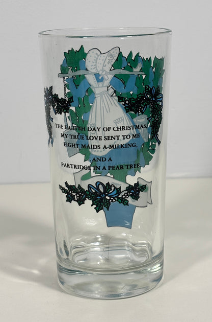 A clear glass drinking tumbler with a Christmas-themed printed design featuring an angel, holly, mistletoe, and a poem about Christmas.