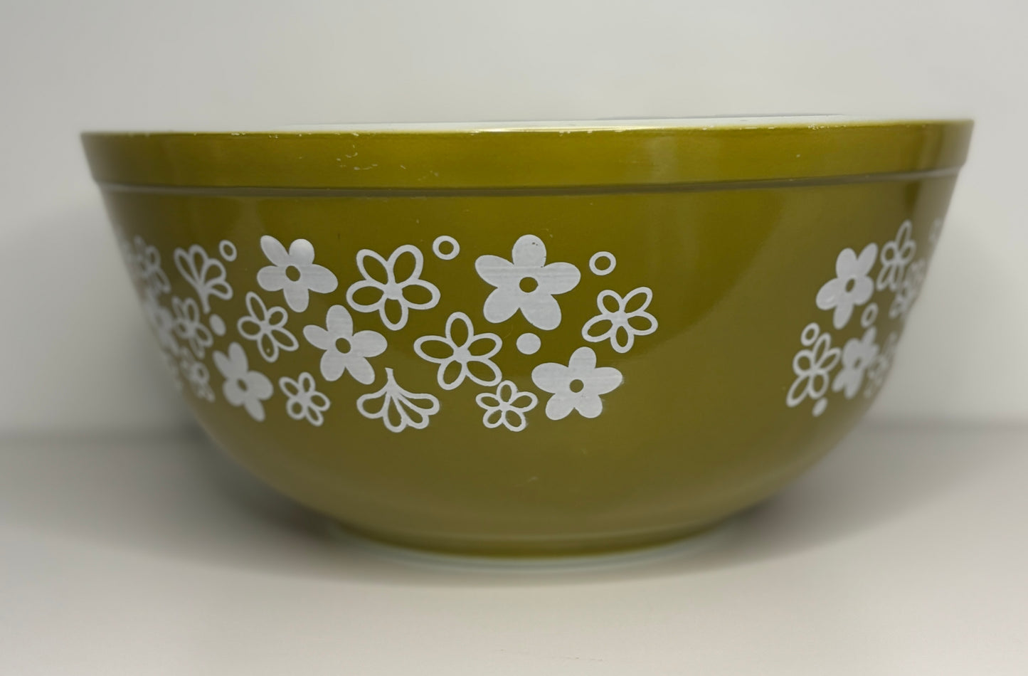 Green bowl with white floral pattern on a white background