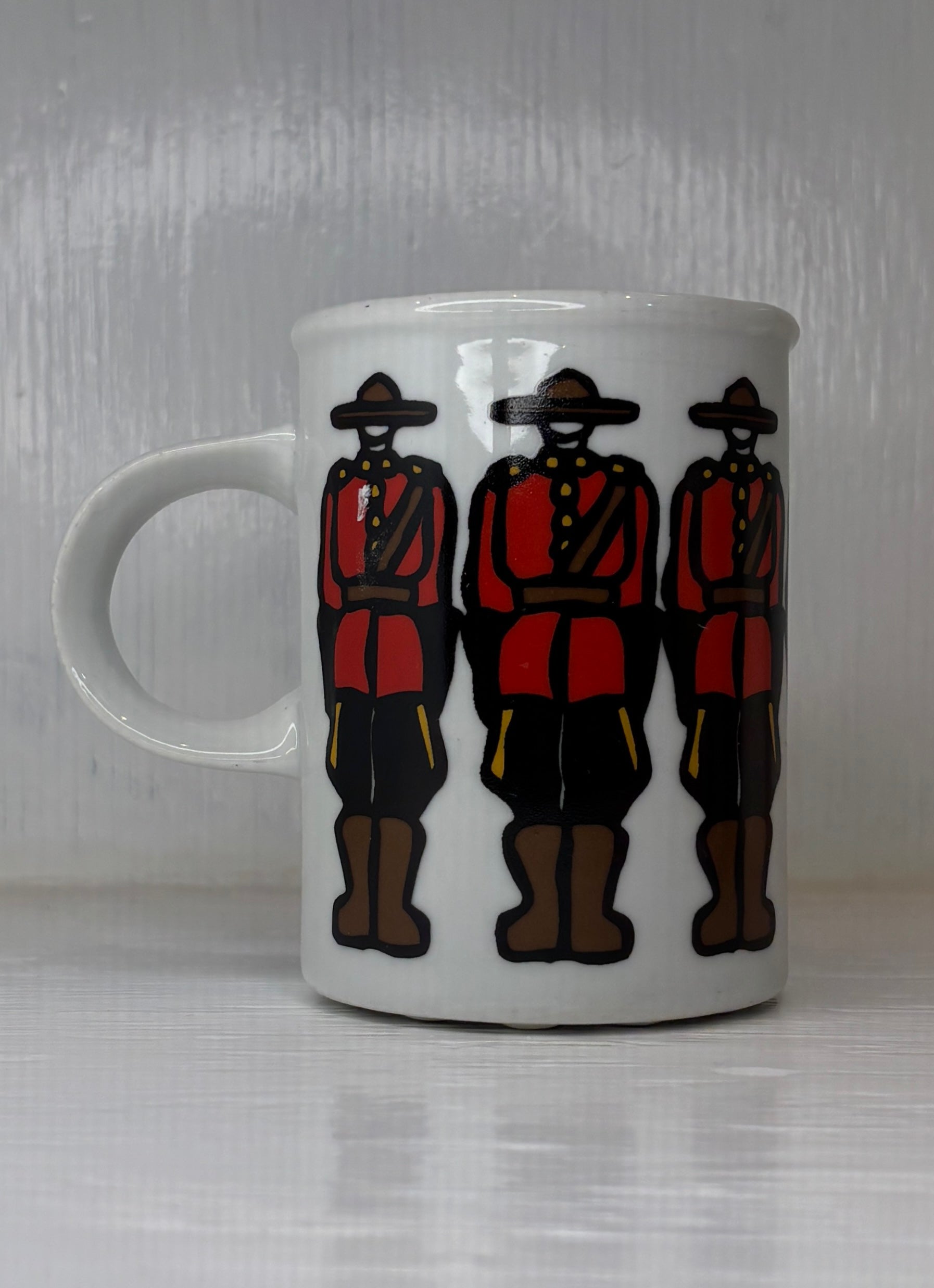 White mug with illustrations of three people in red and black outfits on a white background