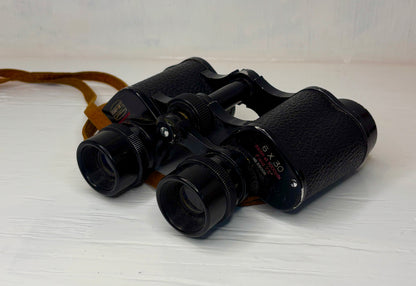Black binoculars on a light wooden surface