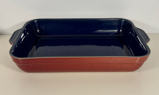 Rectangular ceramic baking dish with red speckled exterior and navy interior on a white background