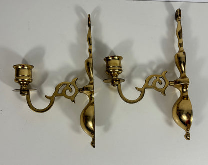 A pair of ornate brass wall sconces with curved arms and candle-style holders, shown against a plain white background.