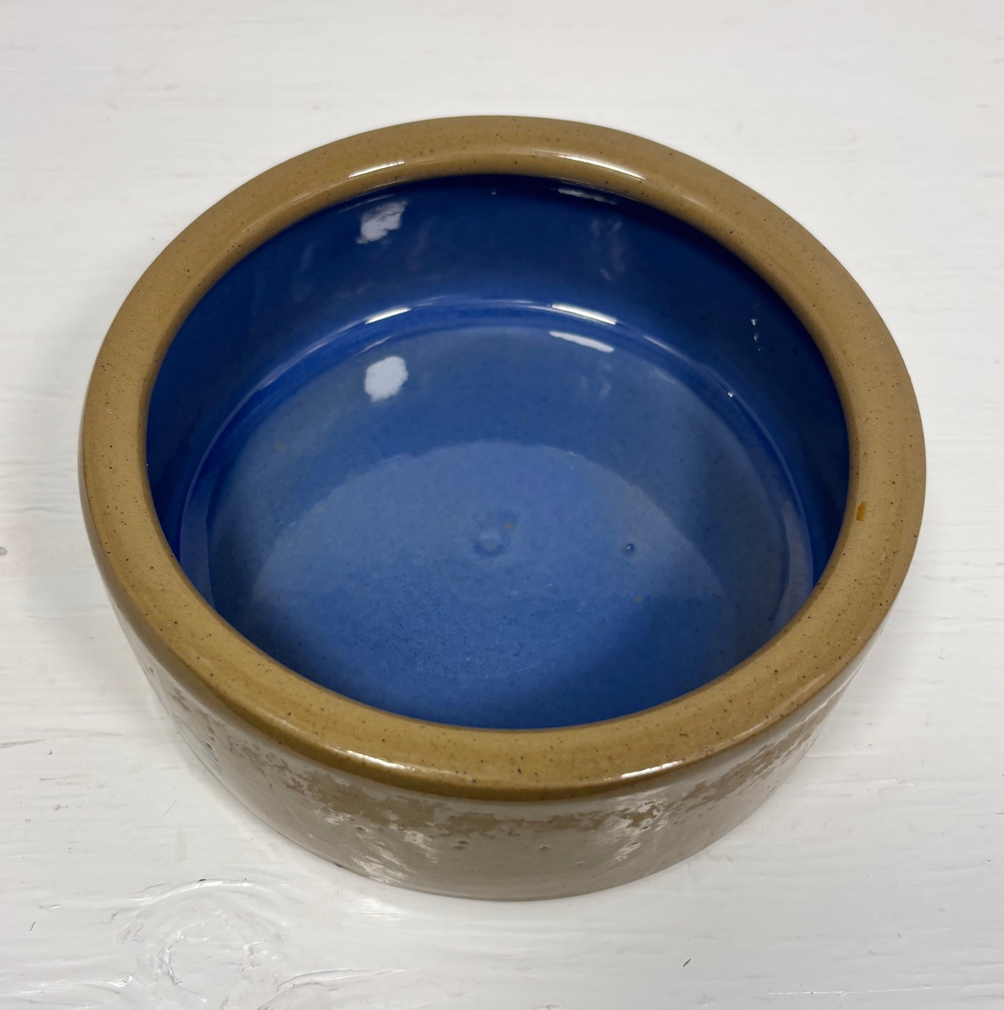 Ceramic bowl with blue interior and brown exterior on a white background