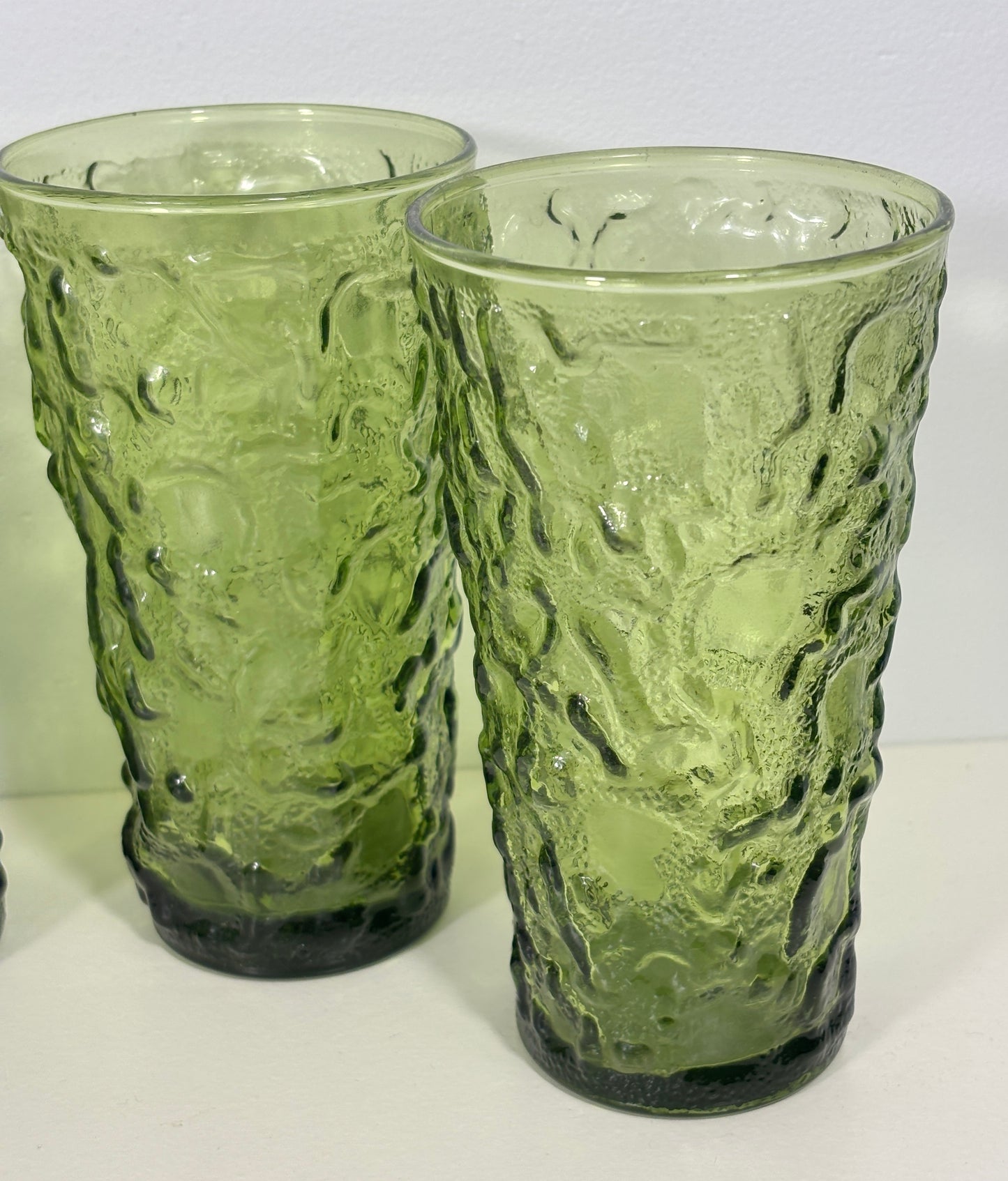 Two green textured glass tumblers on a white surface