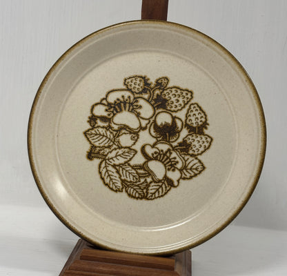 Ceramic plate with floral design on a wooden stand against a white background