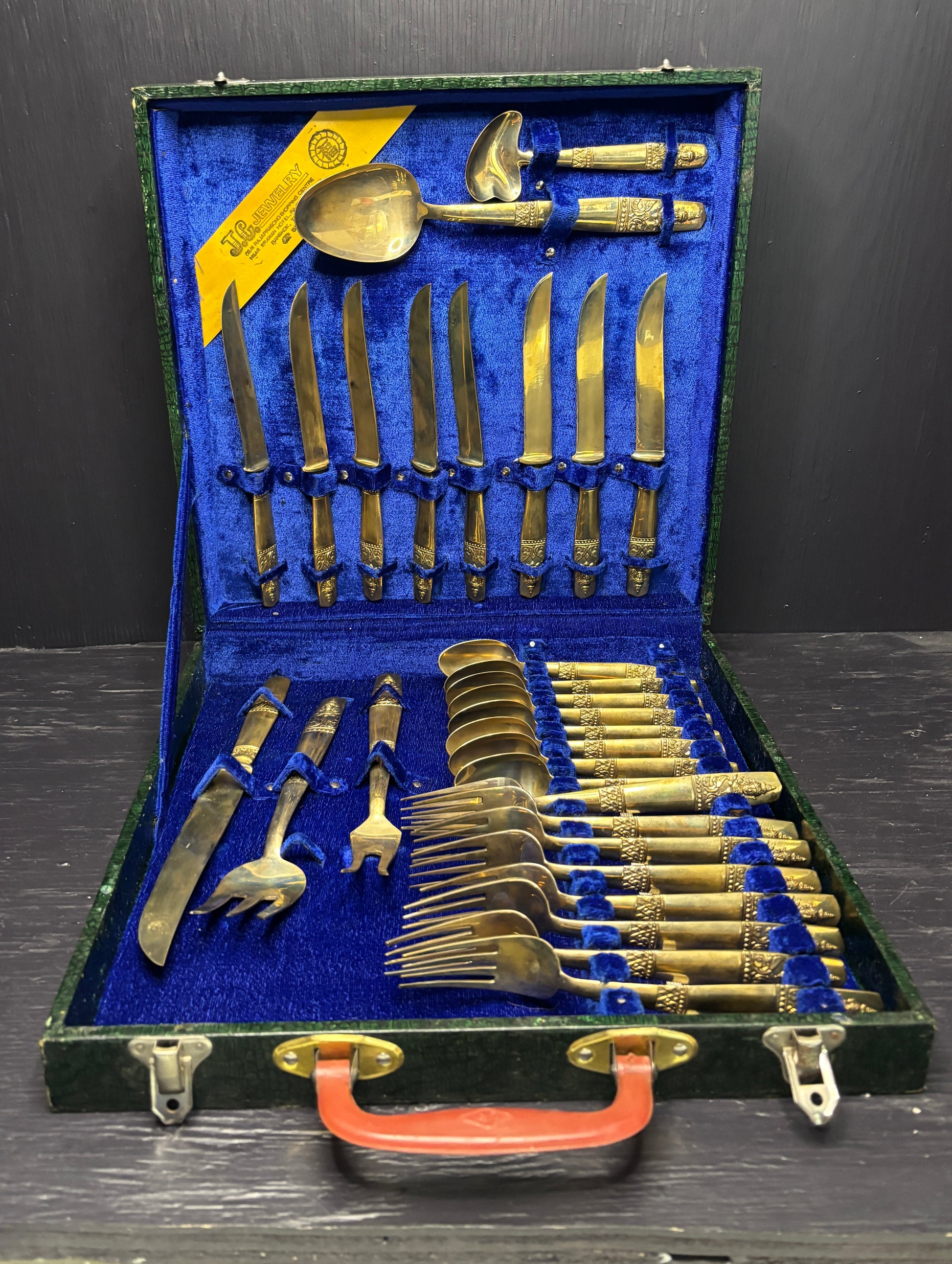 Set of gold and silver cutlery in a blue-lined case on a dark surface.