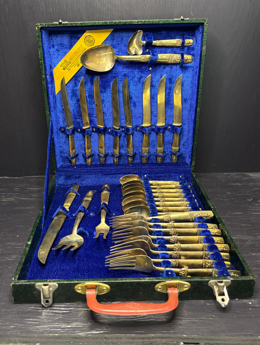 Set of gold and silver cutlery in a blue-lined case on a dark surface.
