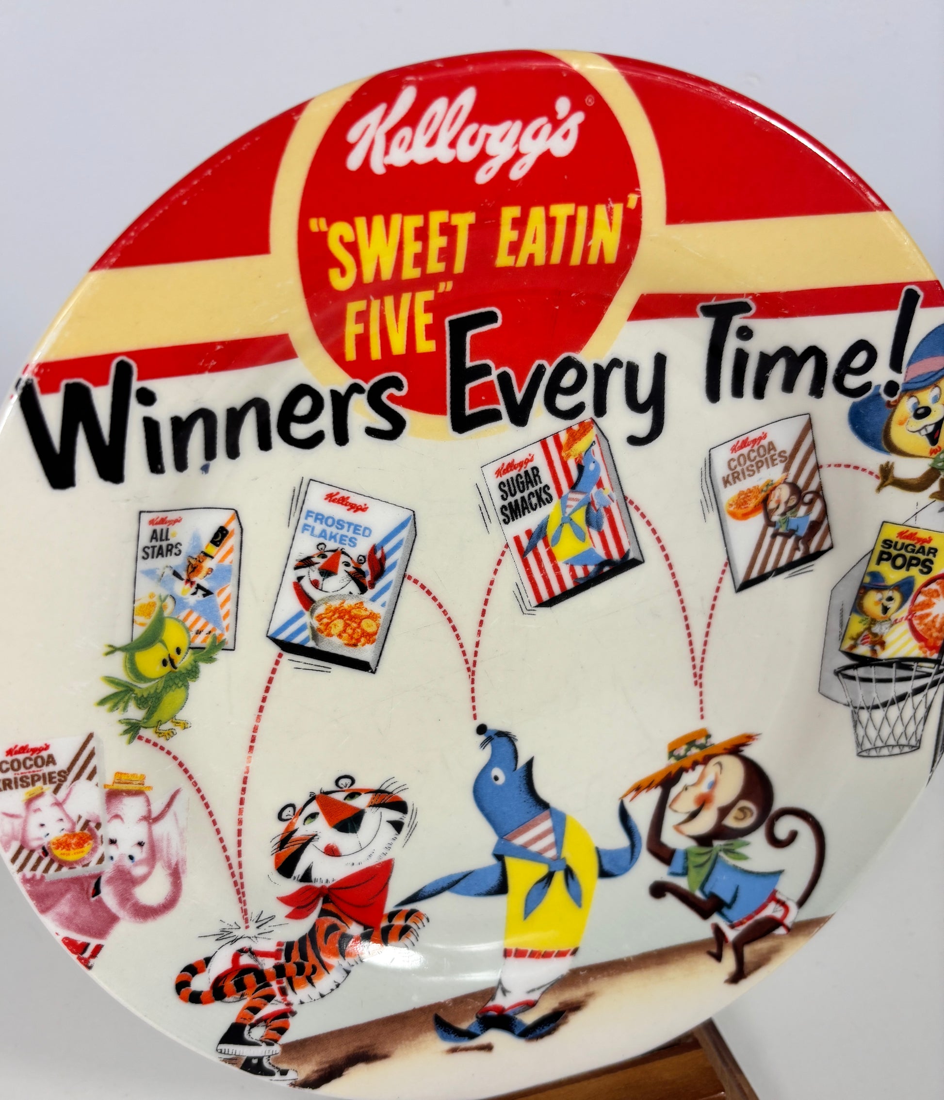 Kellogg's promotional plate with cartoon characters and cereal boxes on a white background