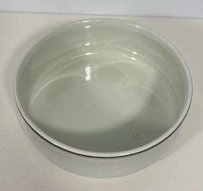 A white ceramic bowl with a thin dark rim, photographed from a top-down angle on a light surface.
