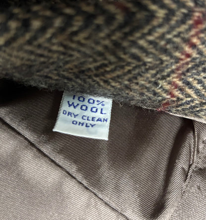 Close-up of a herringbone-patterned fabric with a '100% Wool Dry Clean Only' label.
