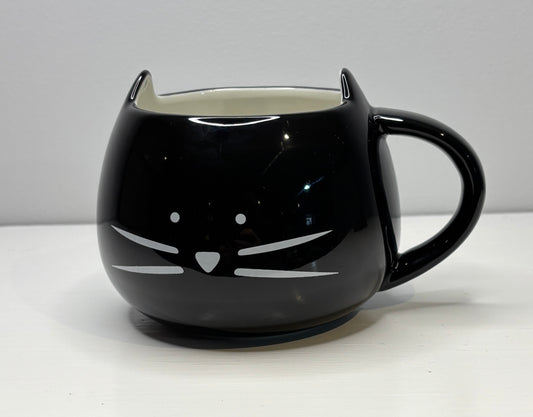 Black cat-shaped mug on a white surface with a gray background