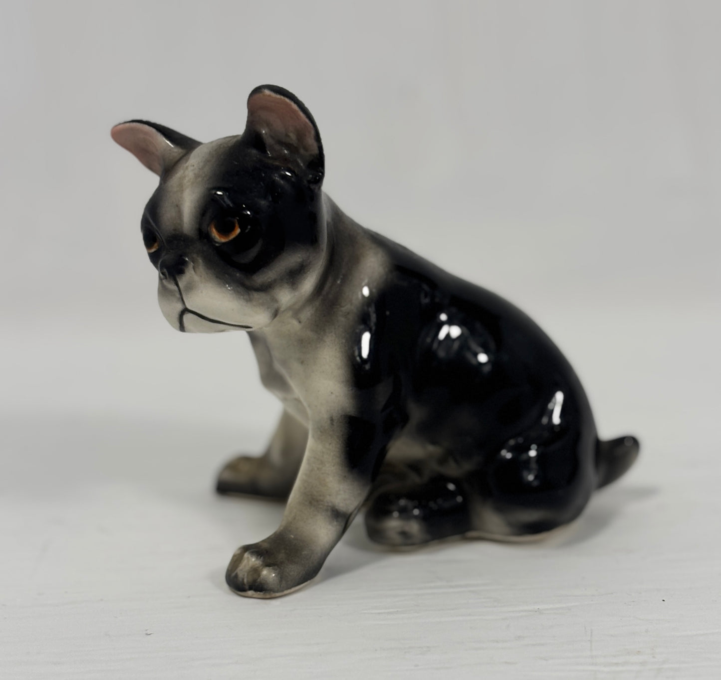 Ceramic figurine of a black and gray dog on a white background