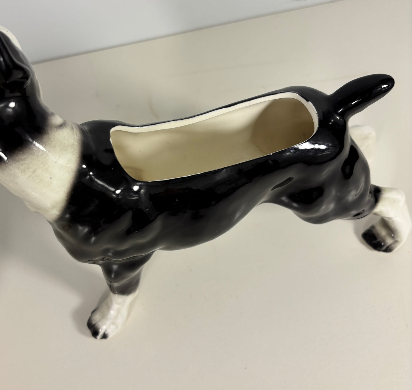 Black and white ceramic dog-shaped planter on a plain background