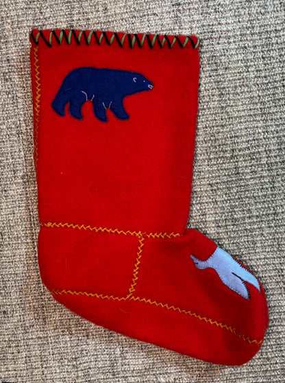 Red felt stocking with blue bear design on a textured surface