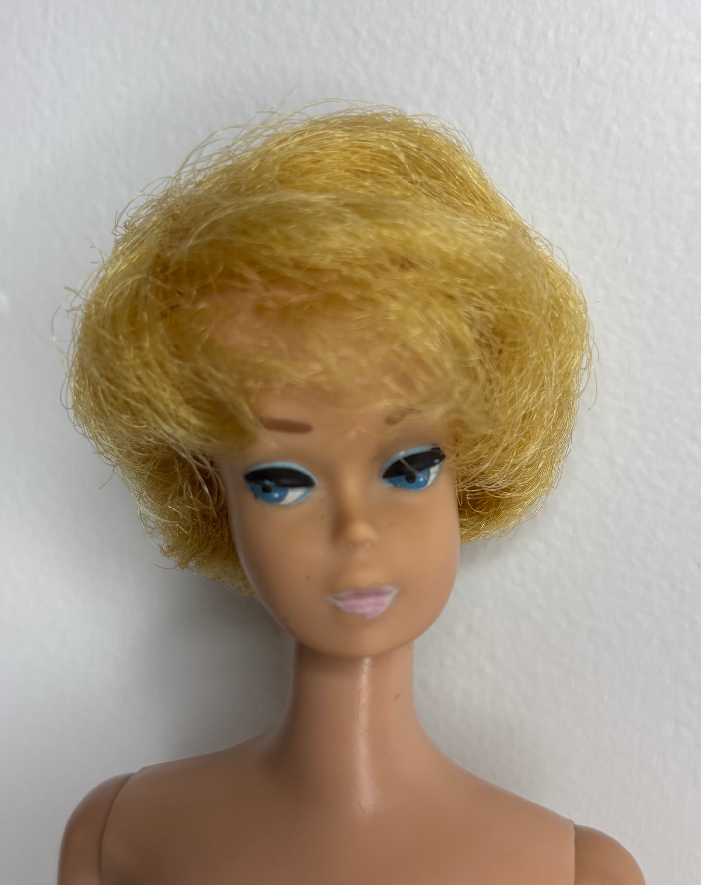 Barbie doll head with blonde wig on a white background