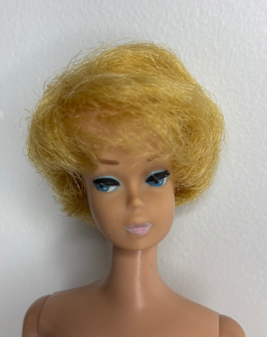 Barbie doll head with blonde wig on a white background
