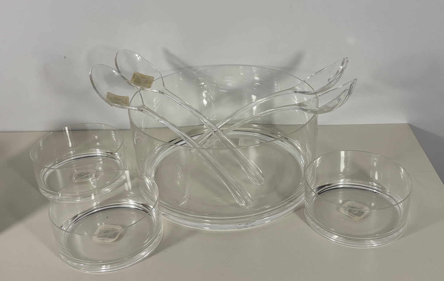 Clear glass serving pieces including a bowl, ladle, and small dishes on a light surface.
