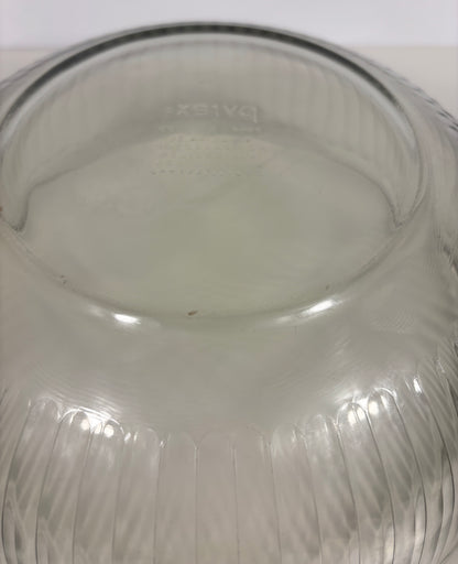 A close-up of a clear ribbed glass bowl or vase viewed from the inside, showing a faint embossed brand mark and vertical fluted texture.