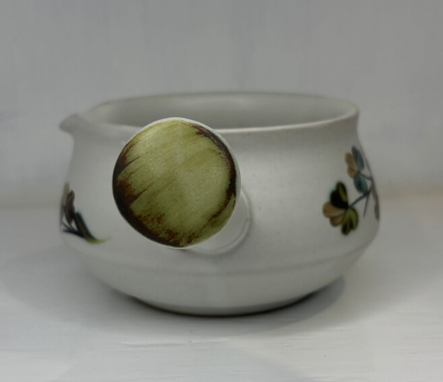 White ceramic pot with floral designs on a white background