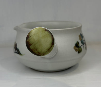 White ceramic pot with floral designs on a white background