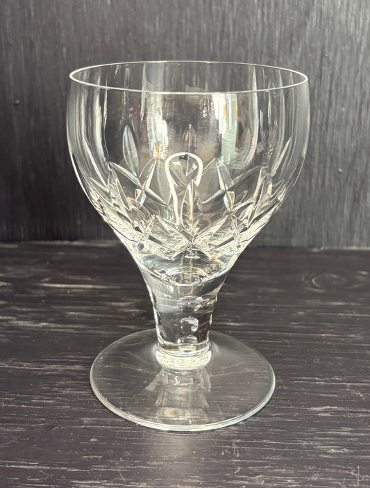 Clear glass goblet with intricate cut design on a dark wooden surface