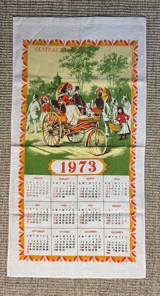 Vintage calendar for 1973 with a decorative border and illustration of people around a horse-drawn carriage.