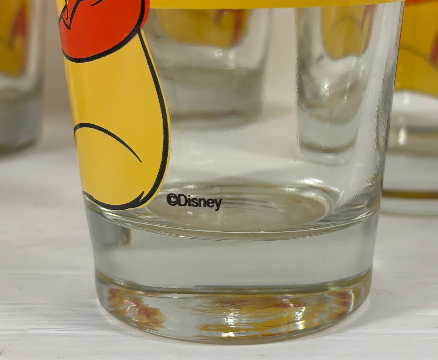 Clear glass with Disney logo and cartoon character on a white surface