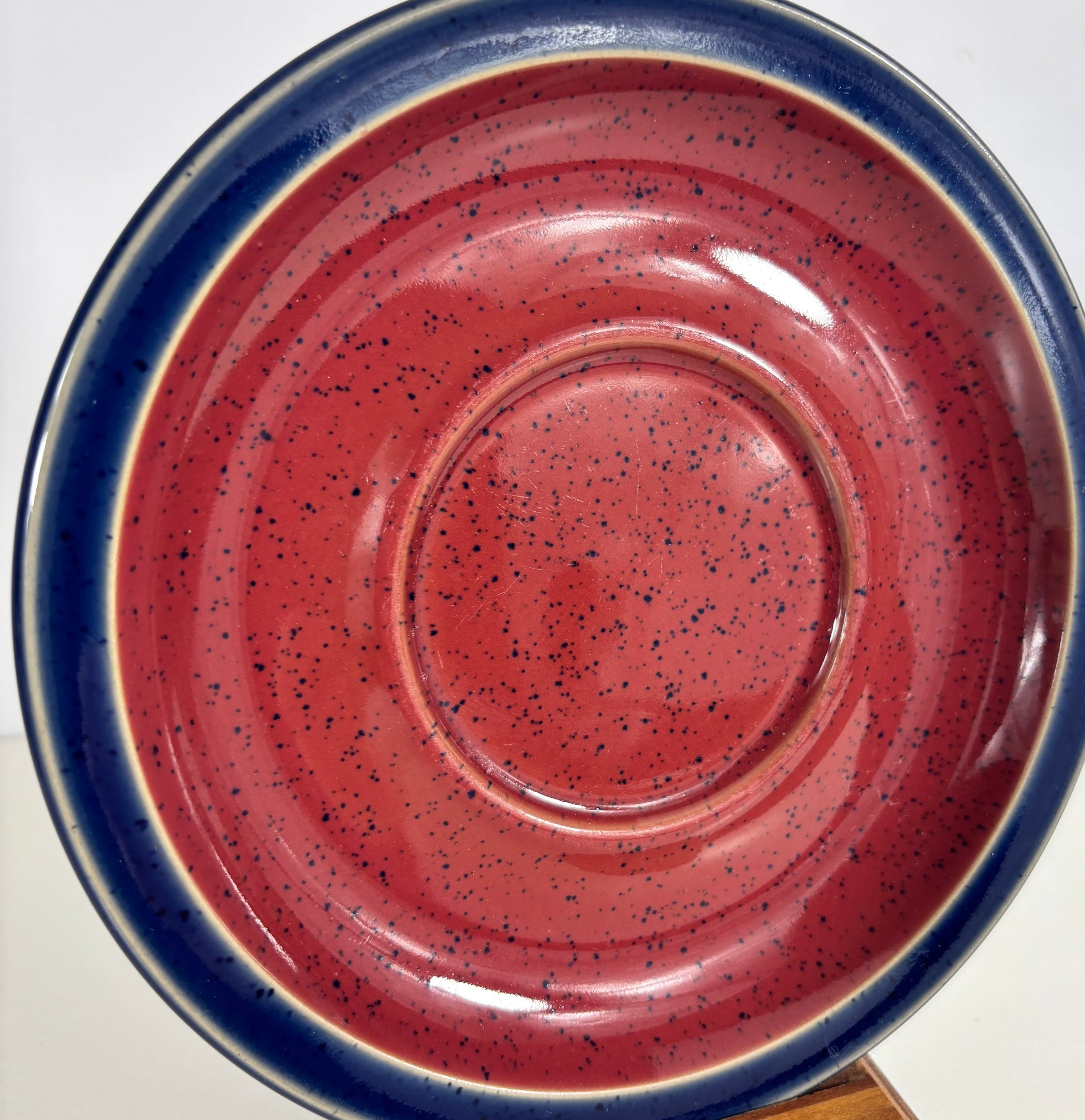 Ceramic plate with speckled design and blue rim on a white background