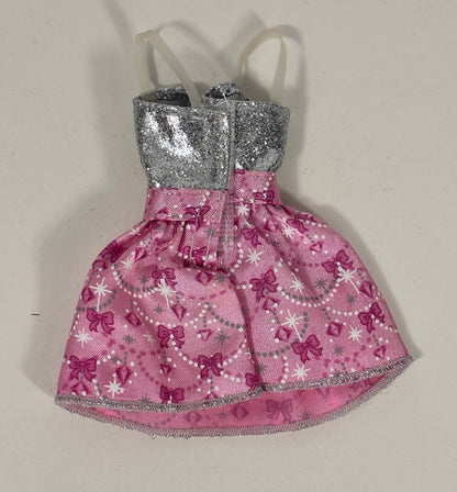 A small pink dress with a silver glittery bodice and white spaghetti straps, decorated with pink bows, white stars, and pearl-like bead patterns.