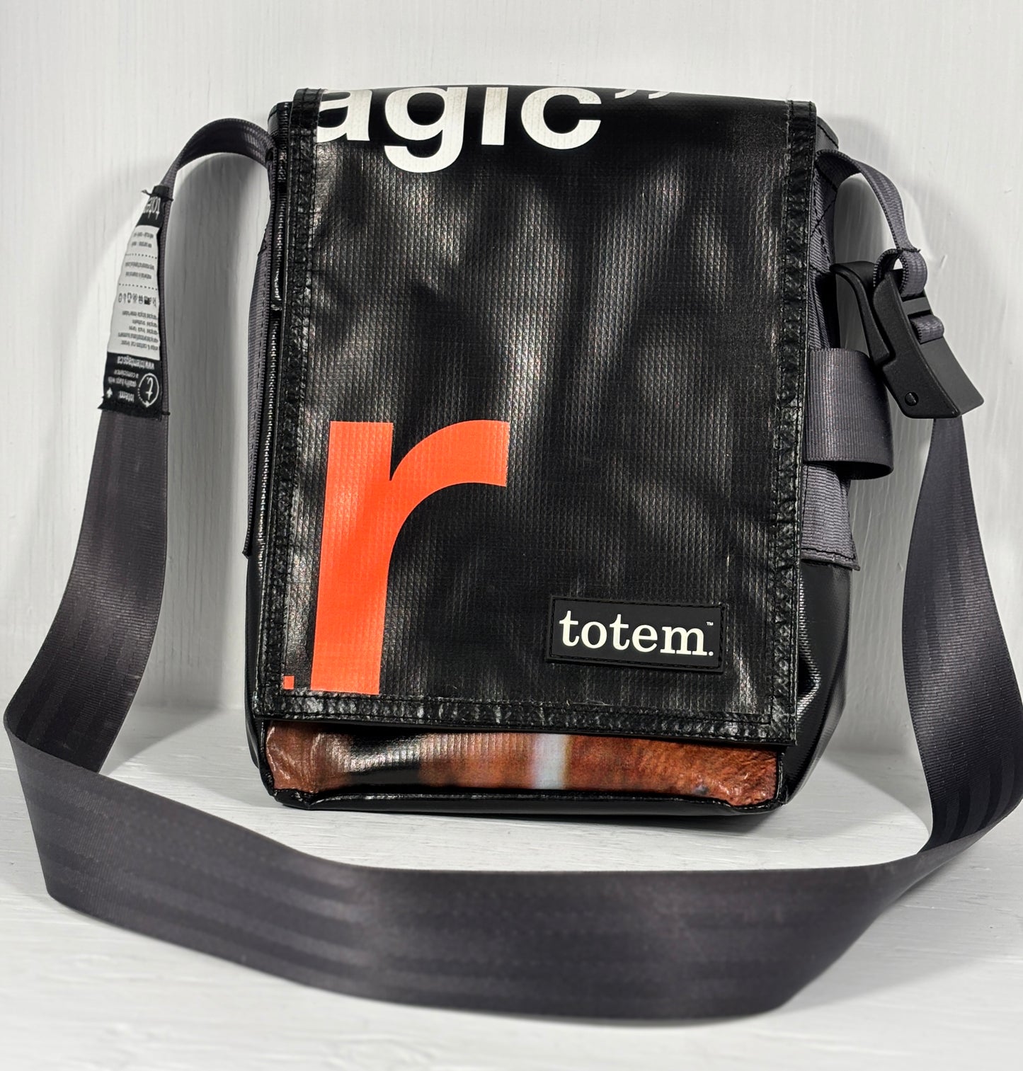 Black shoulder bag with orange 'r' logo and 'totem' branding on a light gray background