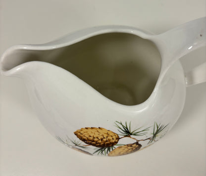 White ceramic pitcher with pine cone design on a white background