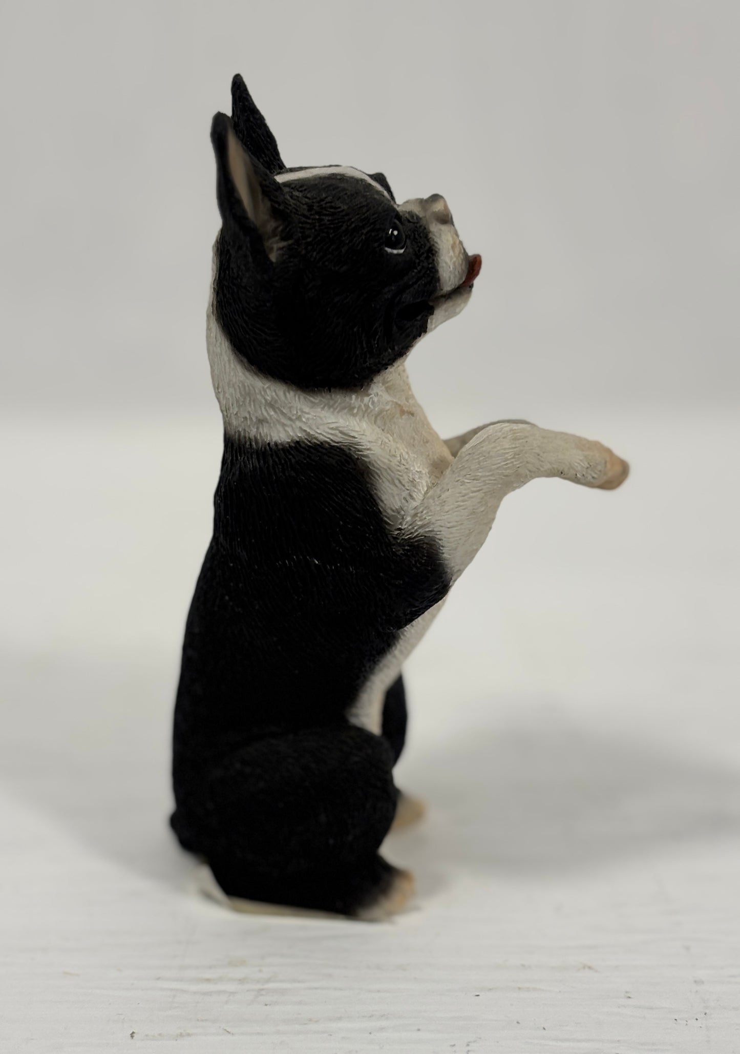 Black and white dog figurine standing on a light gray background