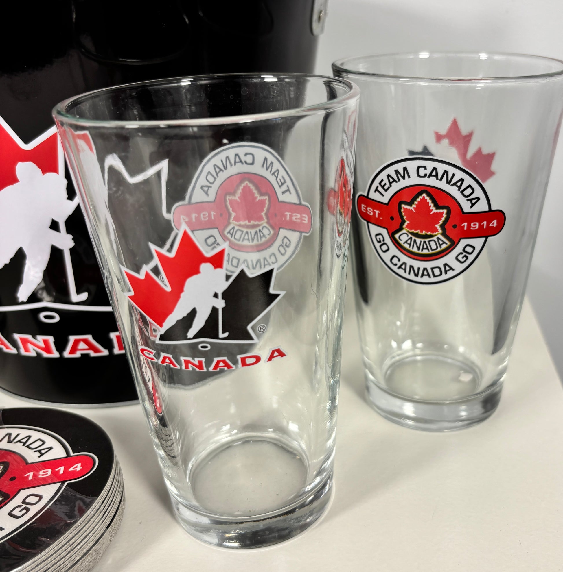 Two clear glasses with Team Canada logos on a white surface