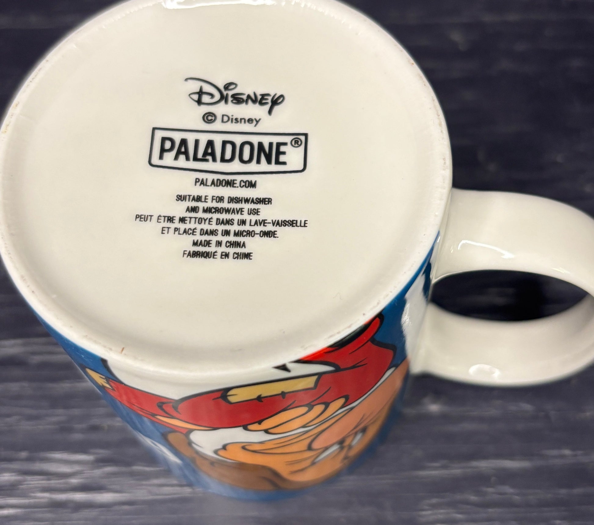 Mug with Disney branding and a cartoon character on a dark surface