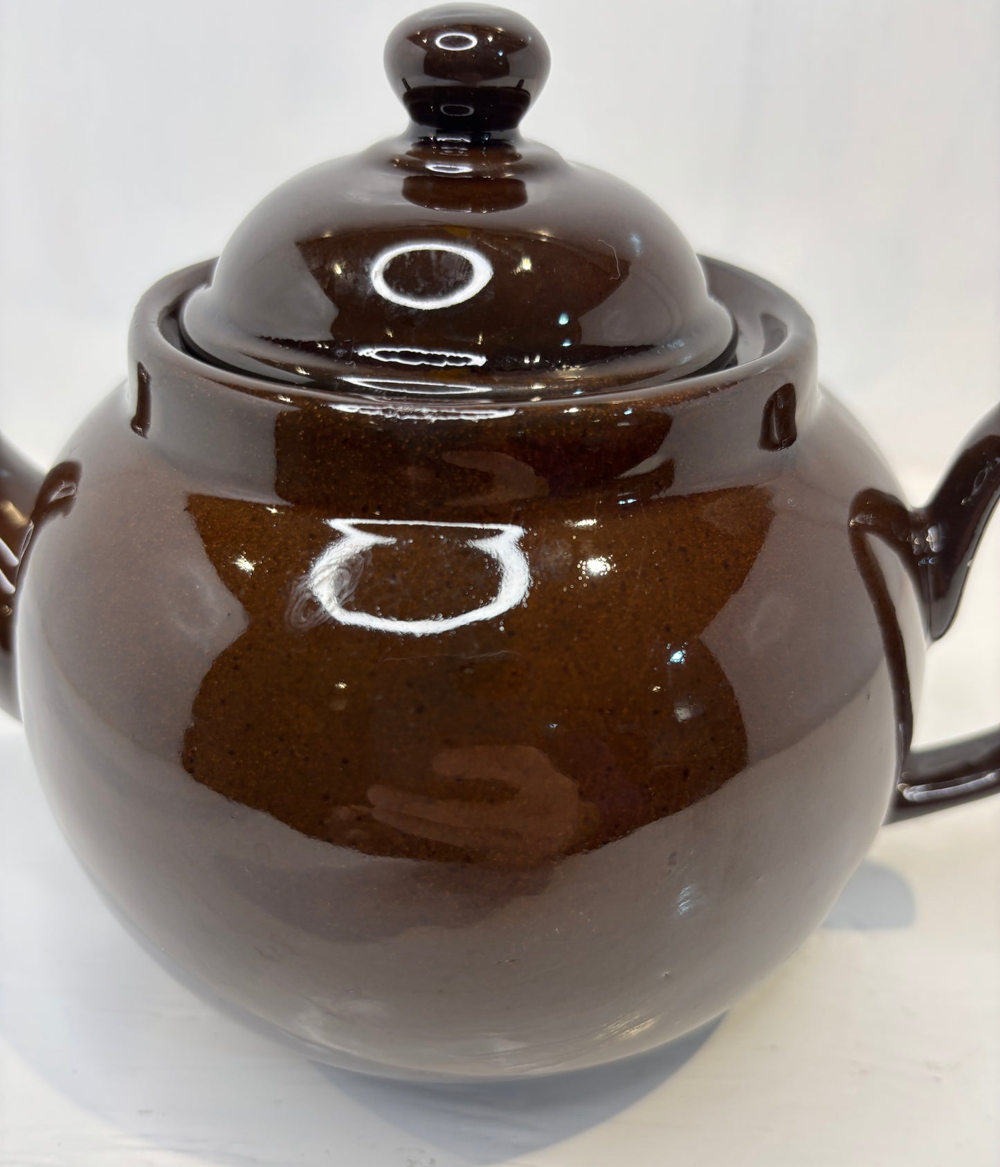 Brown ceramic teapot with lid on a white background
