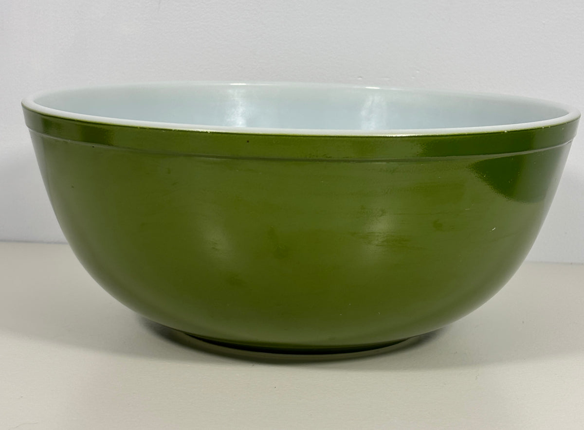 A large mixing bowl with a glossy olive green exterior and a pale blue-gray glazed interior, shown against a plain light background.