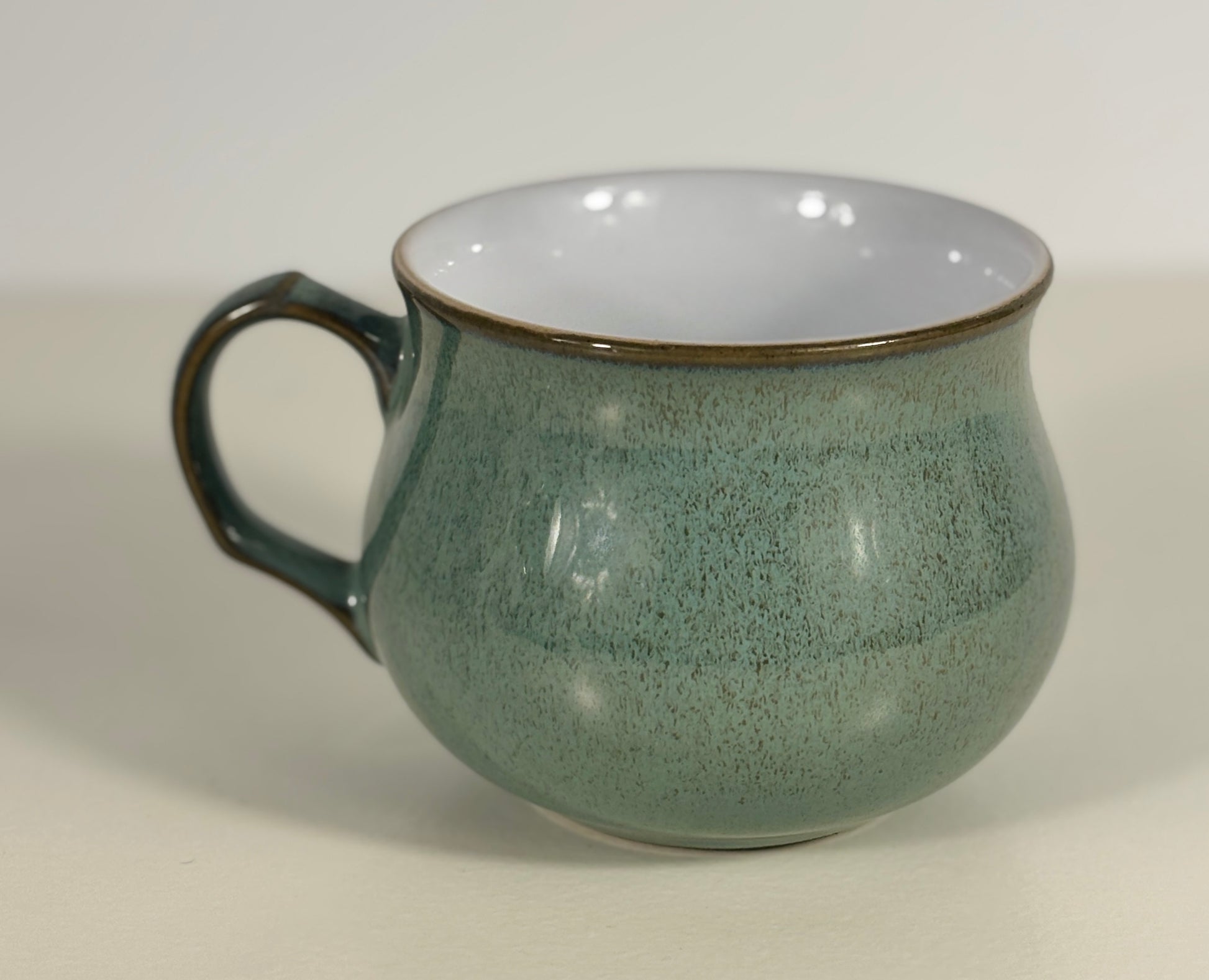 Green mug with a speckled texture on a light gray background