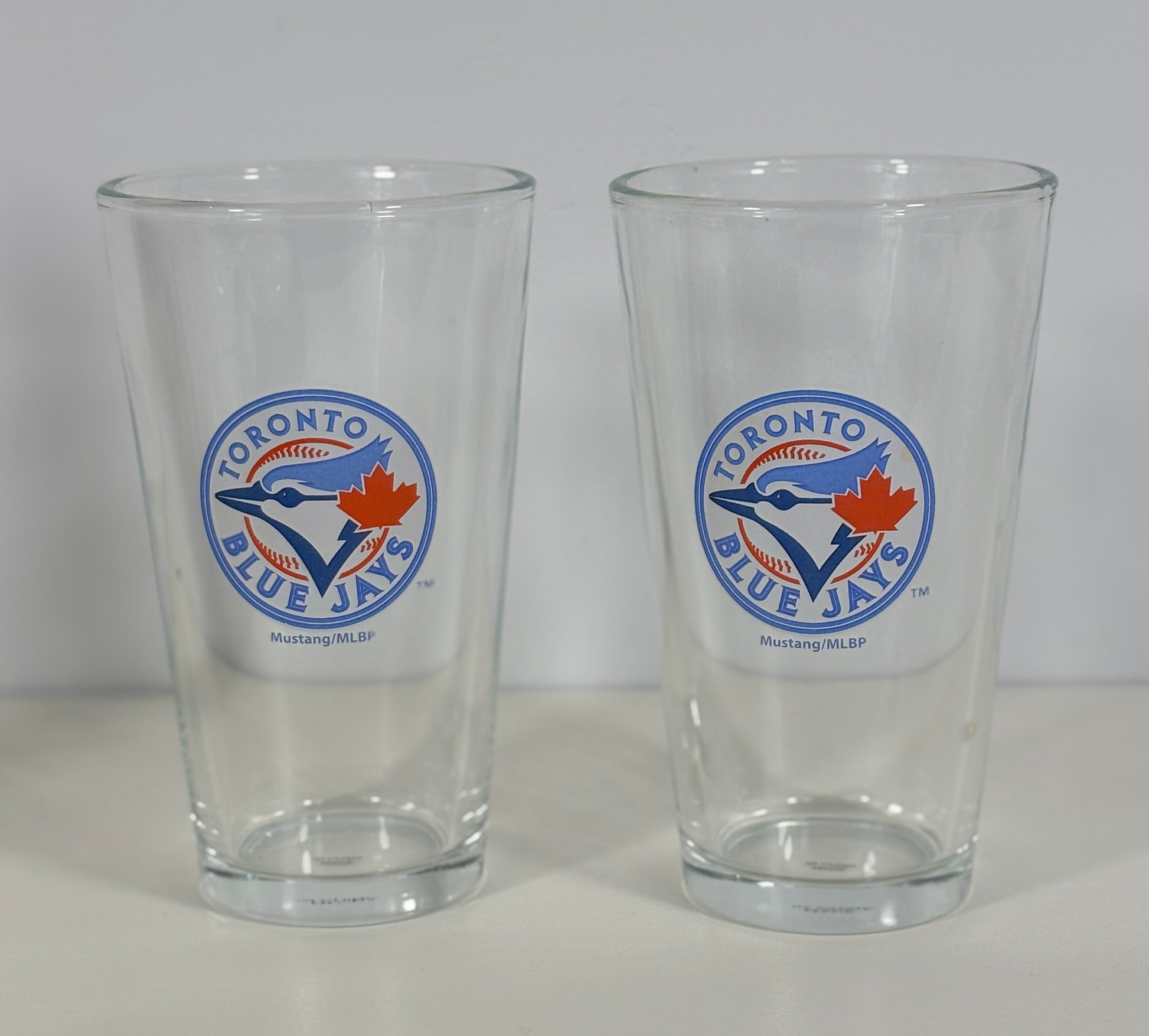 Two clear glasses with Toronto Blue Jays logo on a white background