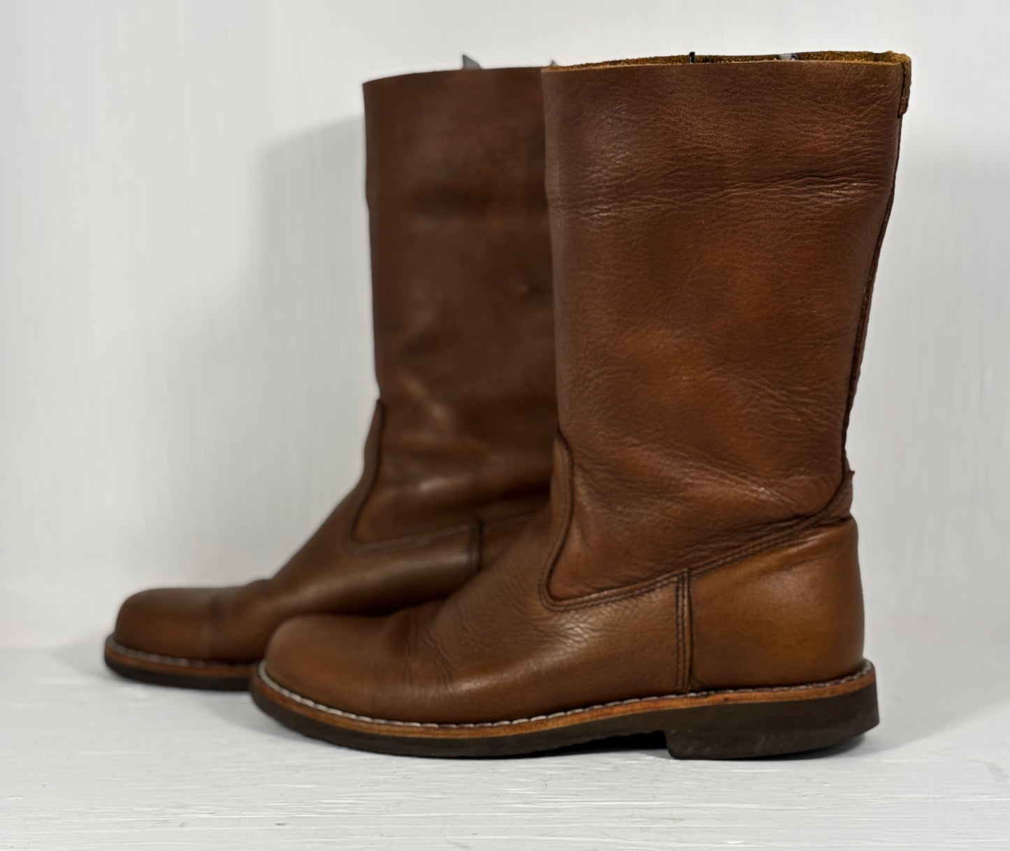 Pair of brown leather boots on a light gray background