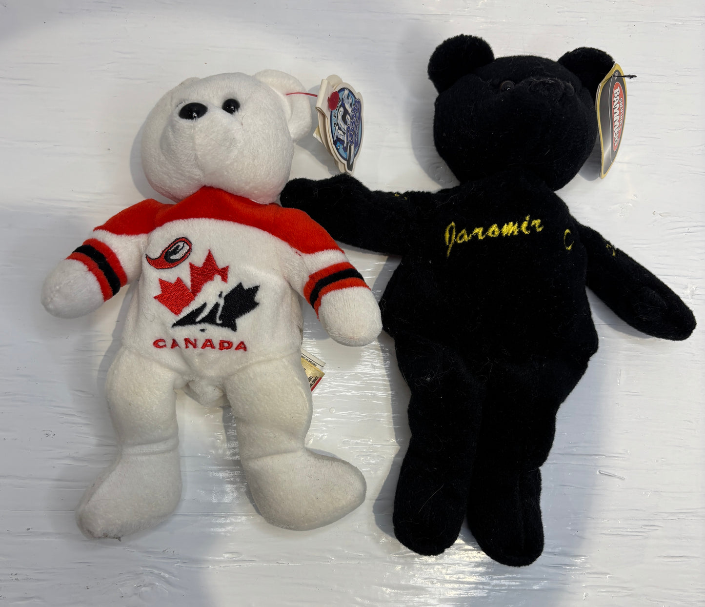 White bear plush toy with red shirt and black maple leaf design, and black bear plush toy with 'Jaramir' text on a white background.