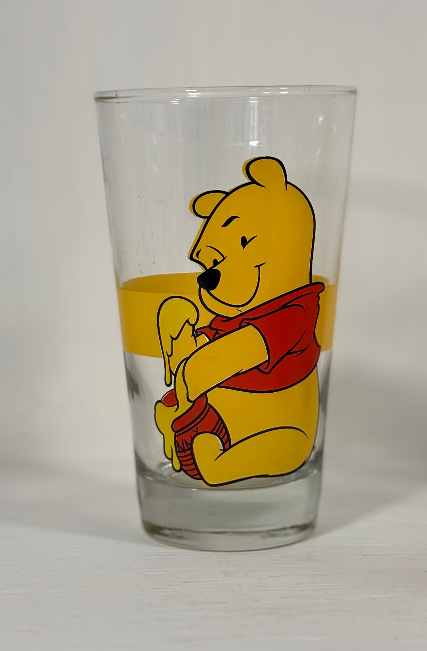 Glass tumbler with Winnie the Pooh design on a white background